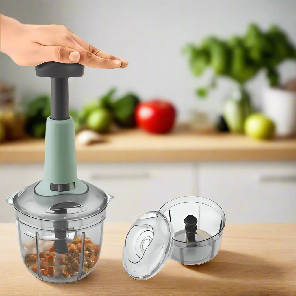Handheld food chopper on a kitchen counter with ingredients inside, kitchen background.