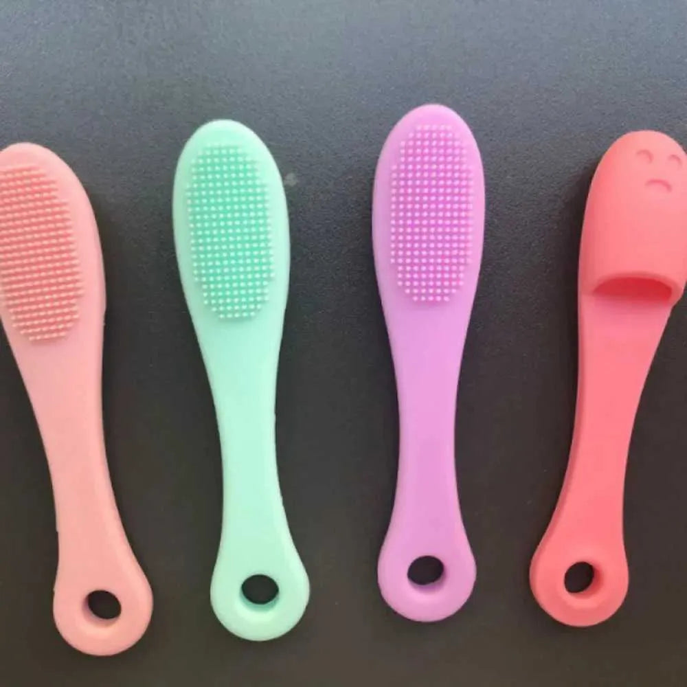 Four baby brushes with different colored handles on a dark background