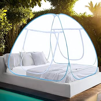 Mosquito net over a bed in an outdoor setting with greenery.
