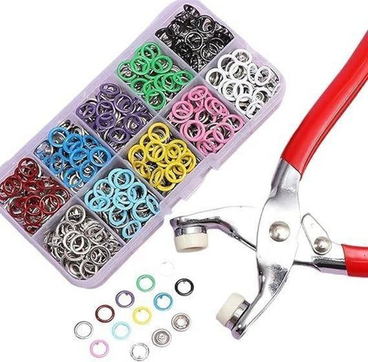 Assorted colored jump rings in a box with a metal plier on a white background