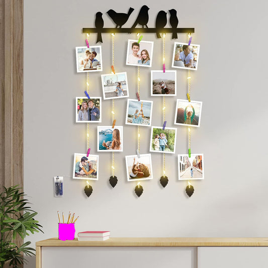 Decorative wall hanging with photo clips and lights on a gray wall.